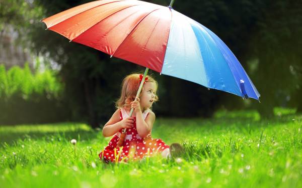 ребенок сидит на траве под разноцветным зонтиком обои для рабочего стола