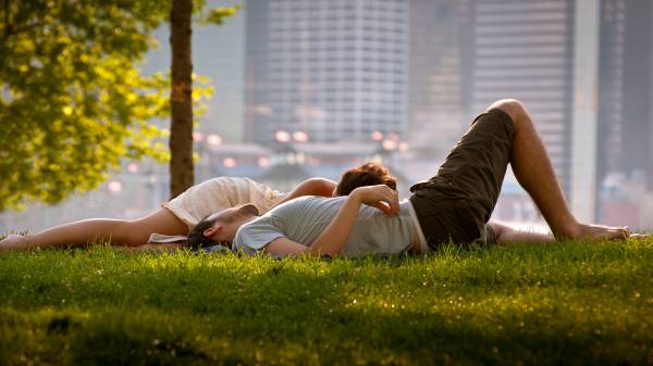парень с девушкой лежат на траве в городском парке обои для рабочего стола