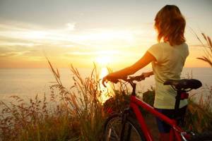 Обои девушка с велосипедом, закат солнца, трава, море на рабочий стол