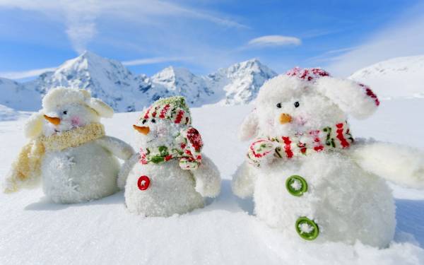 три снеговика на склоне возле заснеженных гор обои для рабочего стола